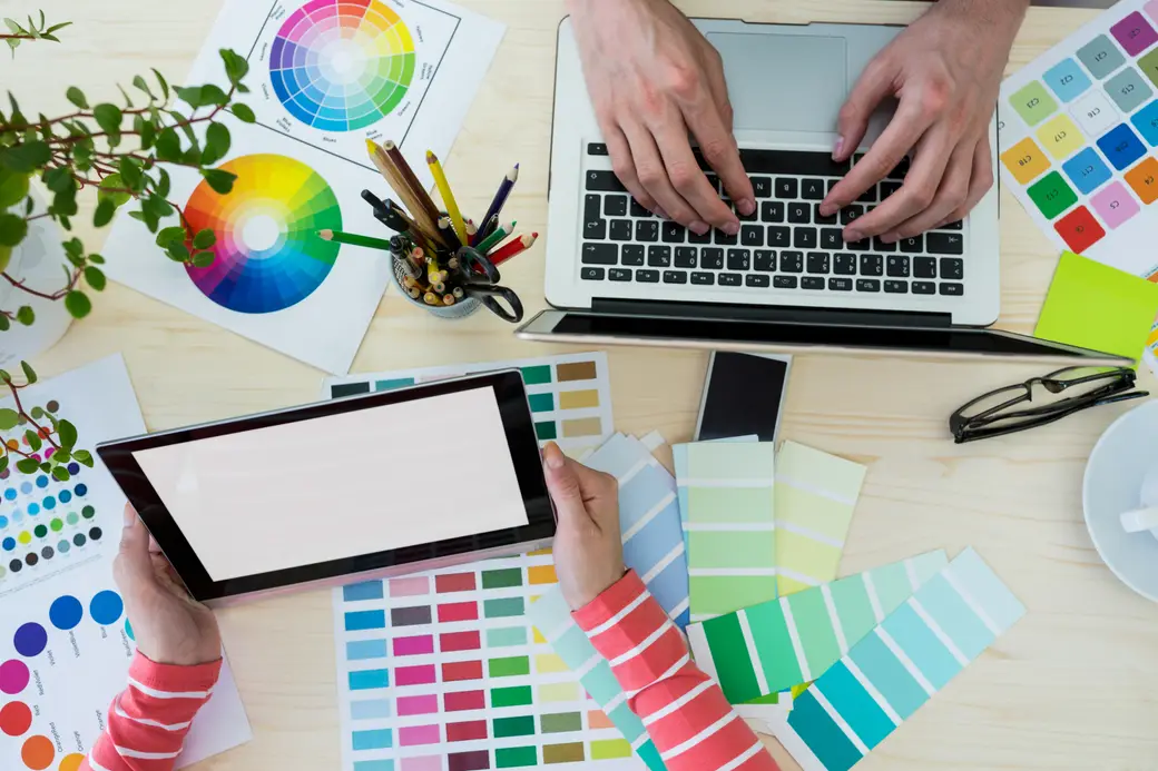 Manos de diseñadores gráficos trabajando con un portátil y una tableta digital