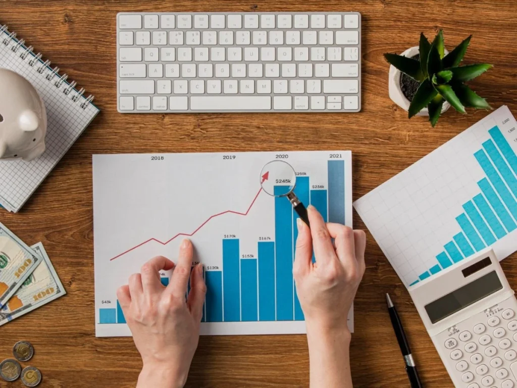 Marketing digital Manos analizando gráficos de crecimiento sobre escritorio con teclado y calculadora, simbolizando los embudos de venta optimizados por Domina Internet en Barcelona.