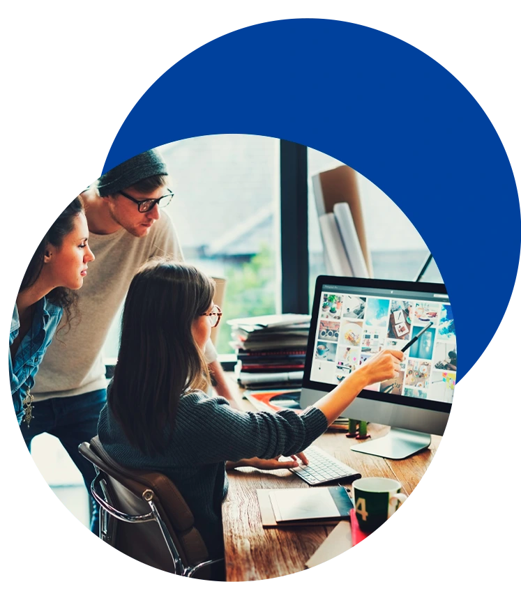 Diseño Web en Barcelona Miembros del equipo de Domina Internet colaborando frente a un monitor con diseños, reflejando nuestra cultura de trabajo creativo en Barcelona.
